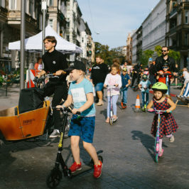 Dorośli i dzieci na rowerach i hulajnogach ruszają z ul. Rayskiego w miasto podczas Rajskiego dnia na Rayskiego